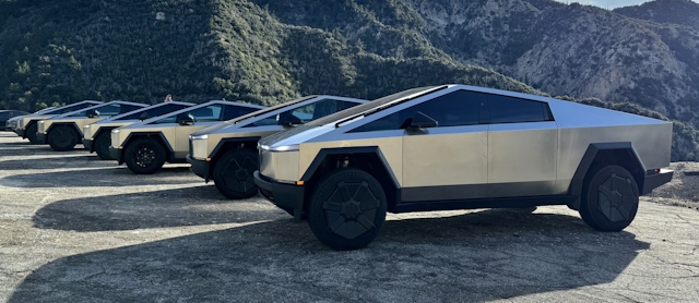 Tesla Cybertrucky zaparkované na odpočívadle vedľa seba s horami v pozadí